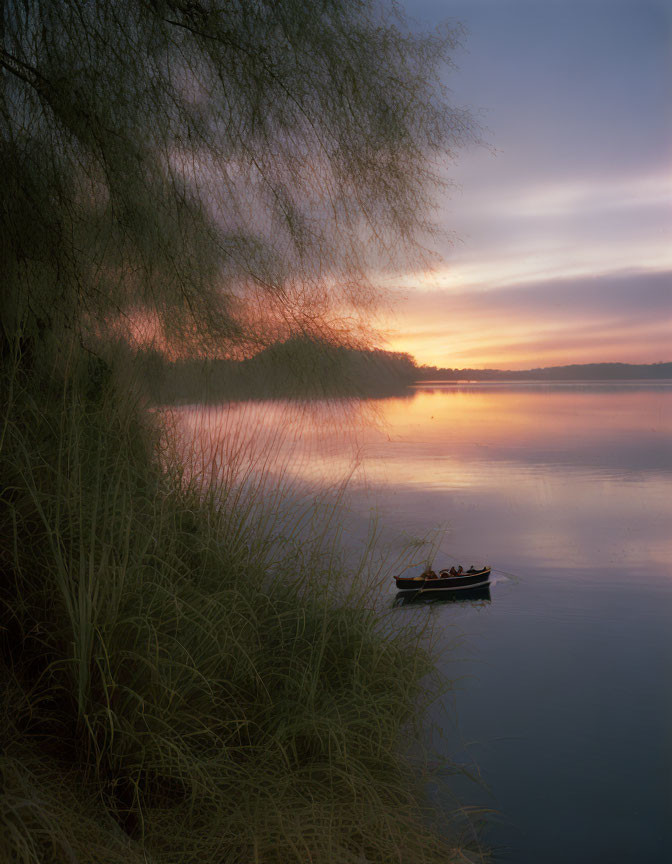 Tranquil lake scene: Twilight, lone boat, two individuals, overhanging branches