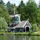 Scenic old watermill on lush riverside with dock and boat