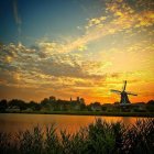 Dutch windmills by tranquil waterway at sunset