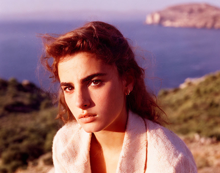 Contemplative woman outdoors at dusk with coastal landscape.