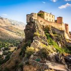 Medieval castle on rugged cliff amid lush greenery