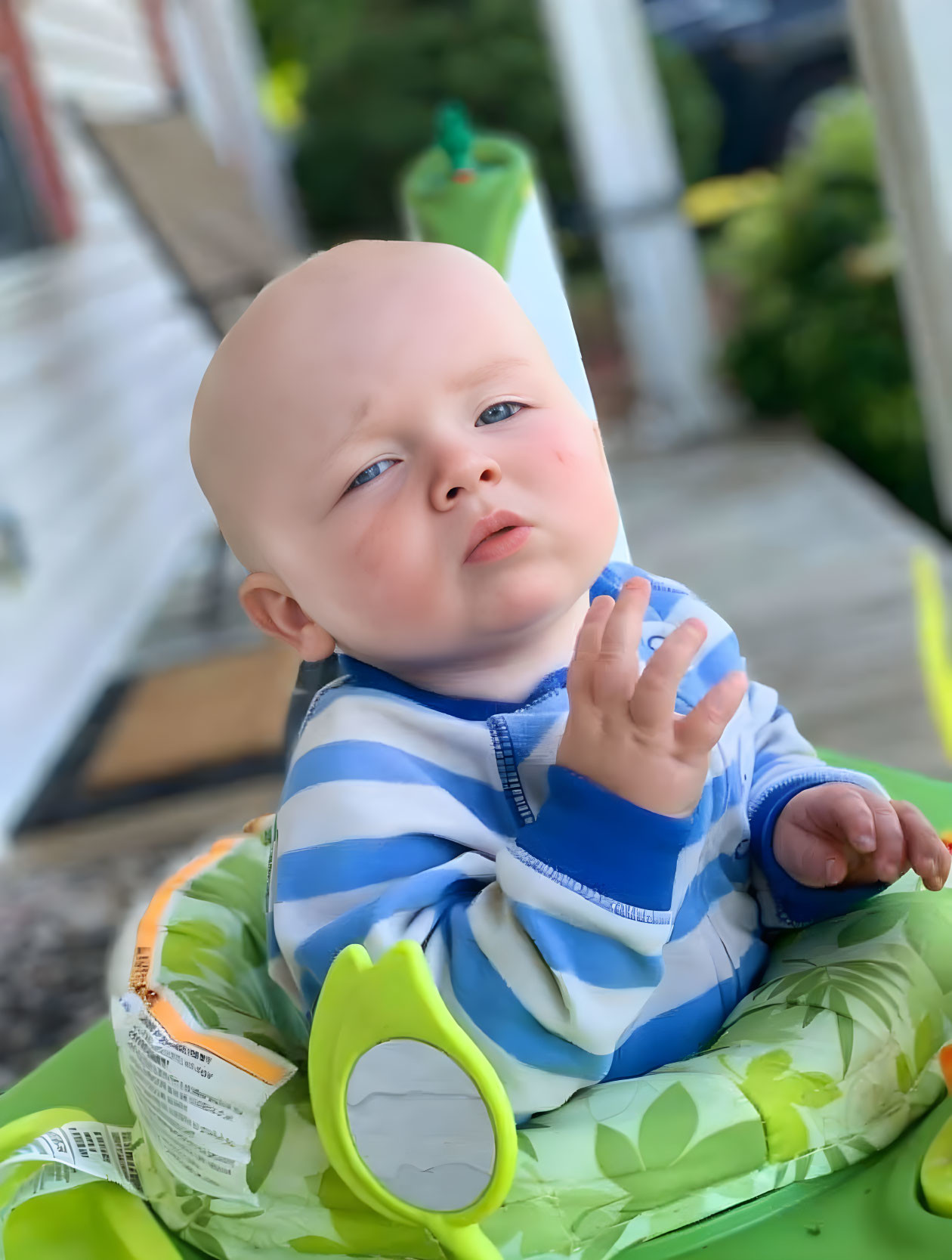 Quizzical baby in blue striped hoodie in green high chair