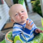 Quizzical baby in blue striped hoodie in green high chair