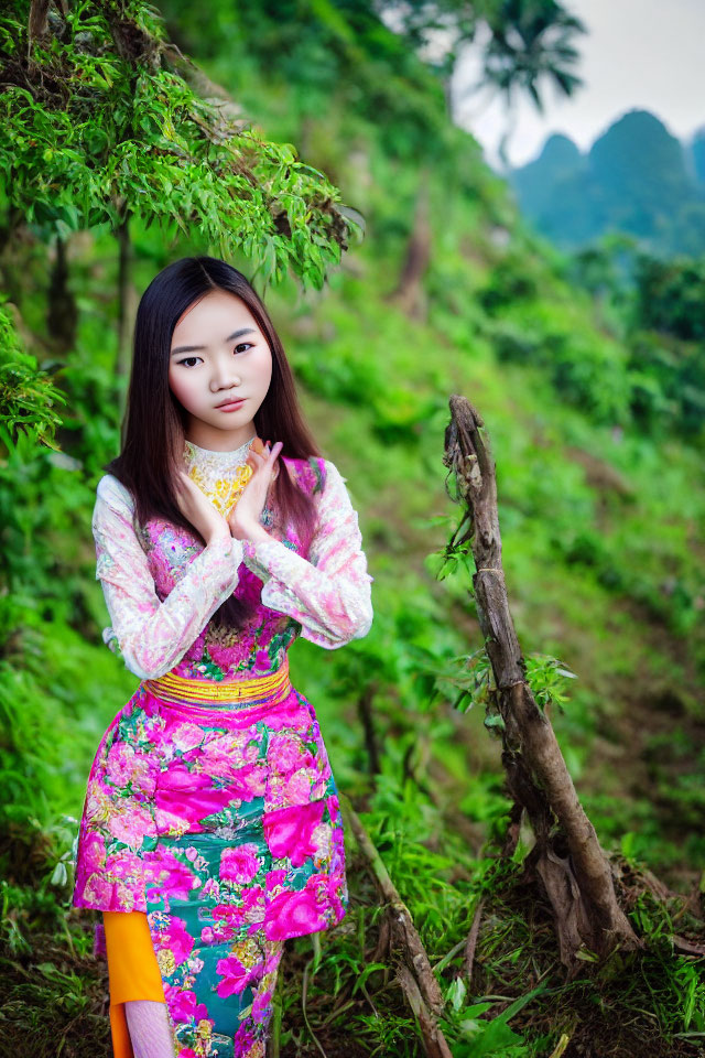 Woman in traditional floral Asian dress surrounded by greenery