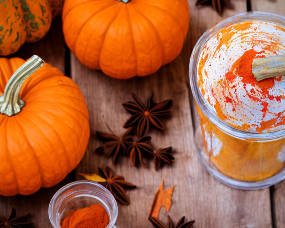 Assorted autumn elements on wooden surface: pumpkins, puree, spices.