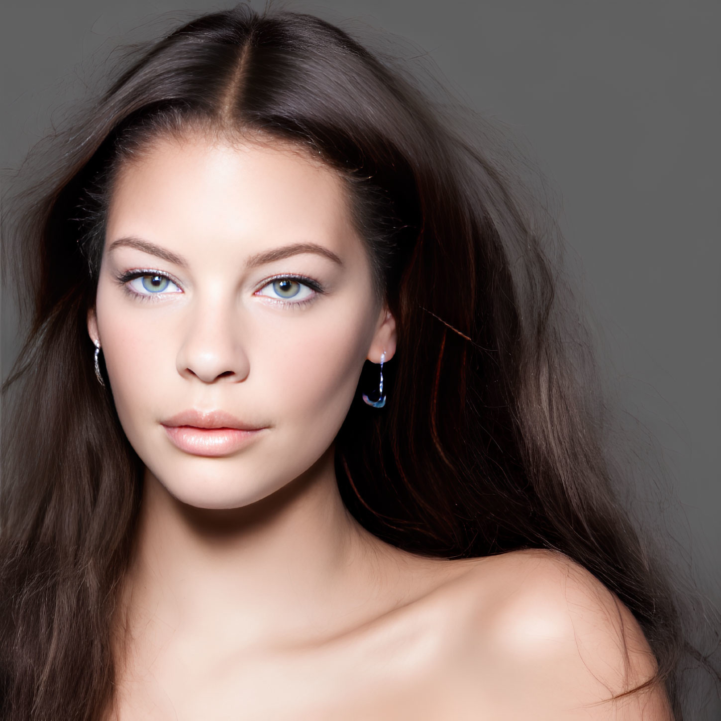 Portrait of a woman with blue eyes and brown hair wearing earrings