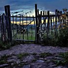 Ornate iron gate leading to whimsical garden with creature-like structure at twilight