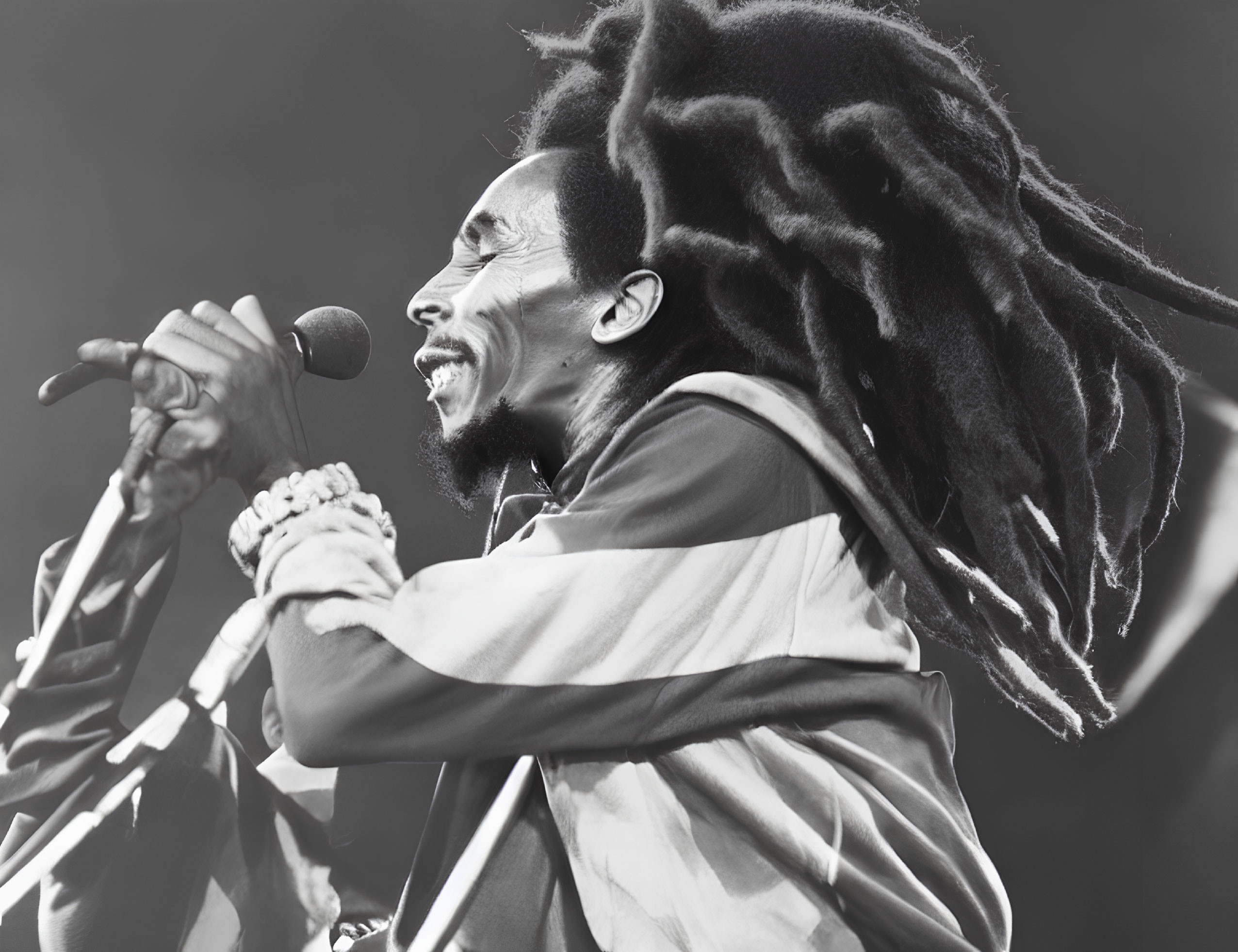 Monochrome image of dreadlocked performer singing on stage