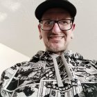 Smiling person in glasses, black cap, Star Wars hoodie