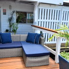 Blue Cushioned Outdoor Seating Area with Grey Sofa and White Railing