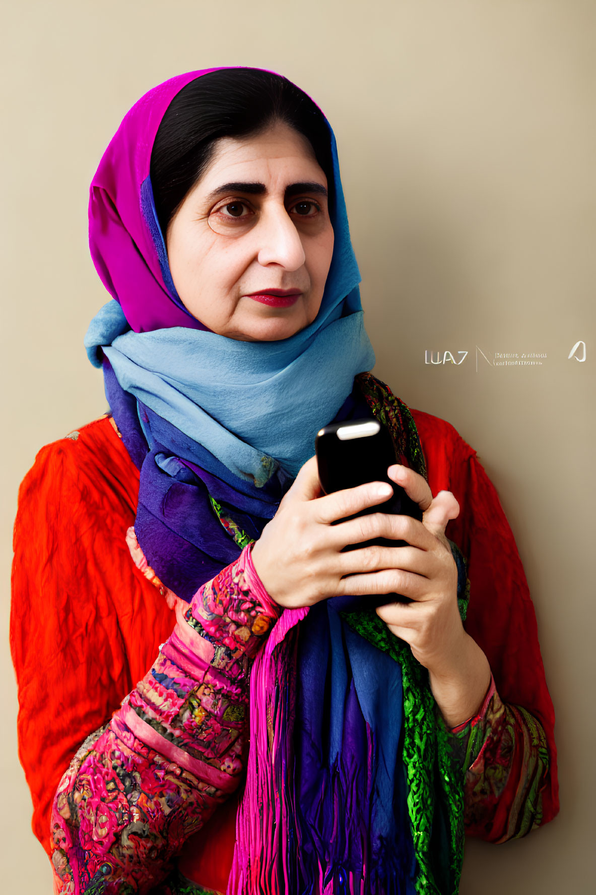 Woman in blue headscarf holding smartphone in orange dress and purple shawl