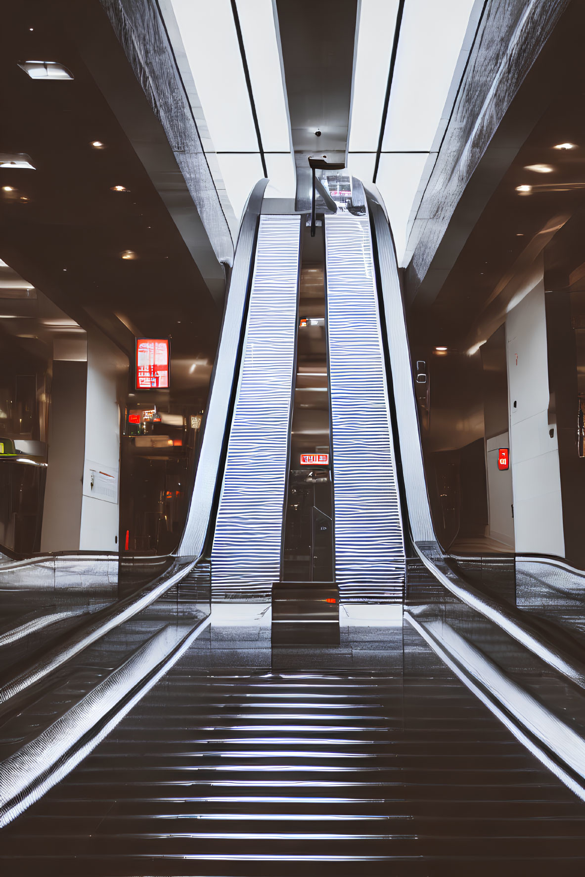 Empty, well-lit indoor space with modern escalator and shiny metal surfaces.