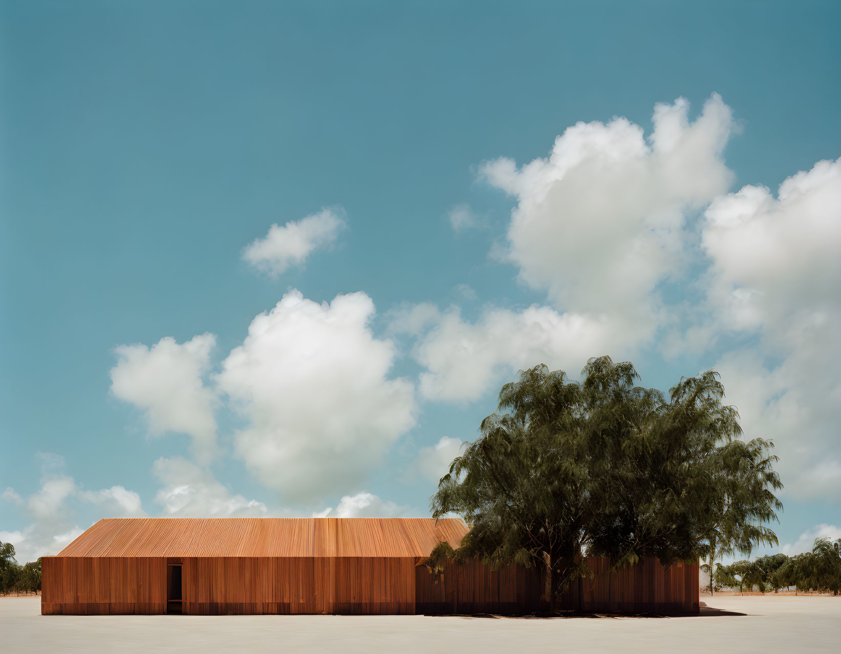 Modern building with rust-colored facade and green tree under blue sky.