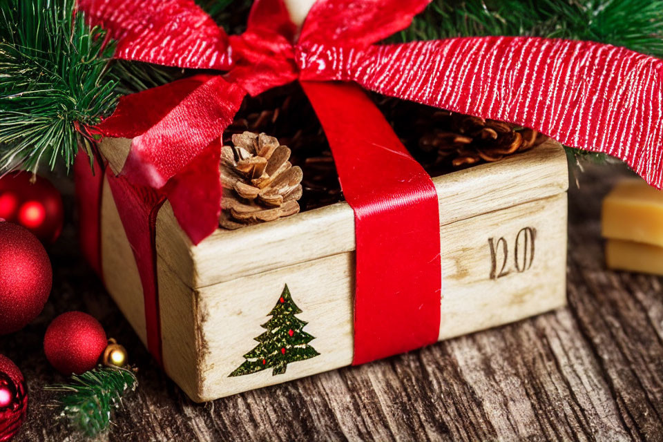 Festive Christmas gift box with red ribbon and pine cones