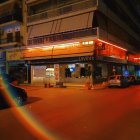 Night scene with warm lighting, car, and light streak under building overhang