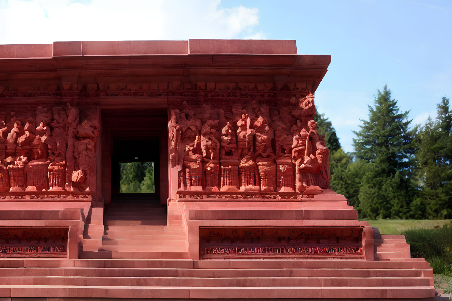 Terracotta temple with intricate bas-relief against blue sky and green foliage