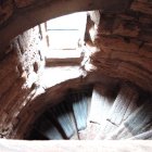 Woman on illuminated staircase surrounded by glowing orbs in ancient building interior.