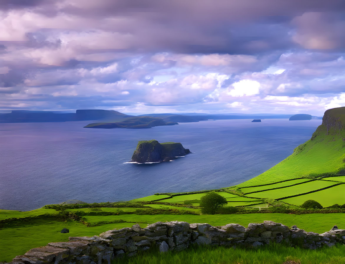 Lush green fields and stone fence in coastal landscape.