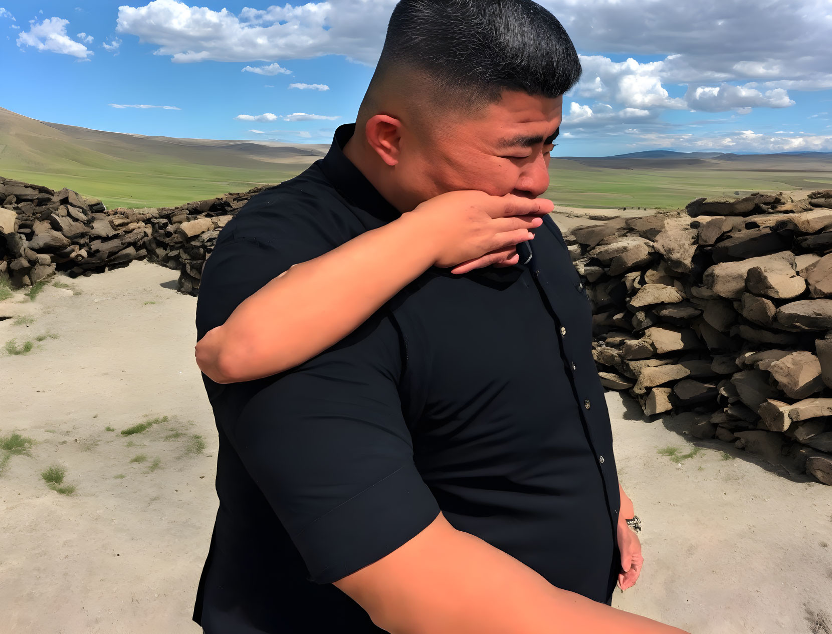 Person in Black Shirt Standing Outdoors Against Sky and Stone Wall