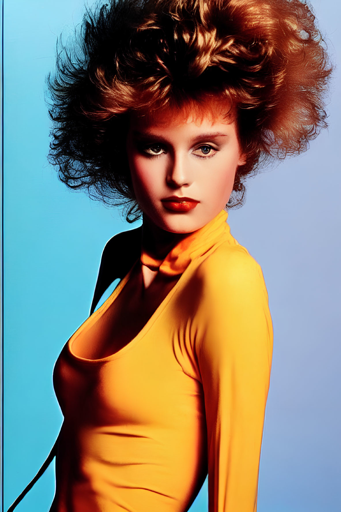 Voluminous hair and striking makeup on woman in yellow top against blue background