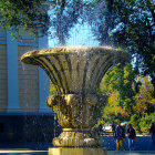 Scenic golden fountain amid autumn trees with walking people