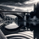 Stone bridge over tranquil river at sunset with city skyline