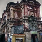 Decaying aged building with graffiti-covered small structure