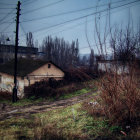 Desolate landscape with dilapidated house and decaying structures.