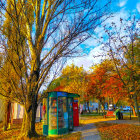 Colorful landscape painting of autumn village scene with rolling hills and strolling figures