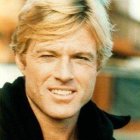 Smiling man with blond hair in flower crown and fur collar