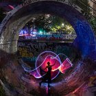 Mystical forest with cloaked figures under curved tree trunk amid purple lights and mist