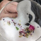 Fantastical creature with antlers and blue eyes in glass dome surrounded by flowers