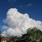 Large caricatured man blending into cloud with smoking pipe, vintage European architecture background