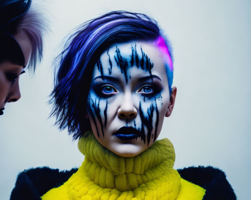 Vibrant purple and blue hair with black tree branch-like facial paint, wearing a vivid yellow t