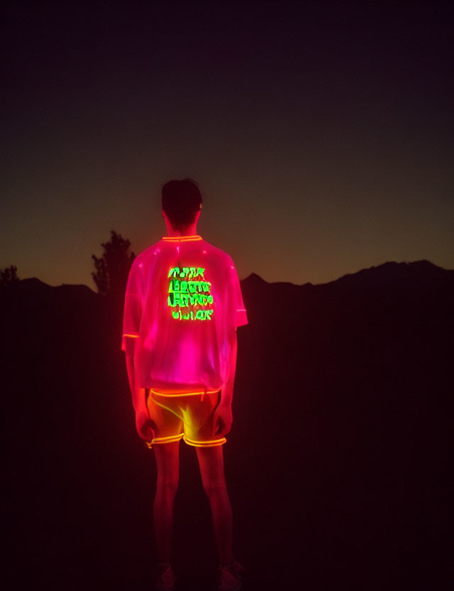 Neon-lit jacket and shorts at dusk against mountain silhouette