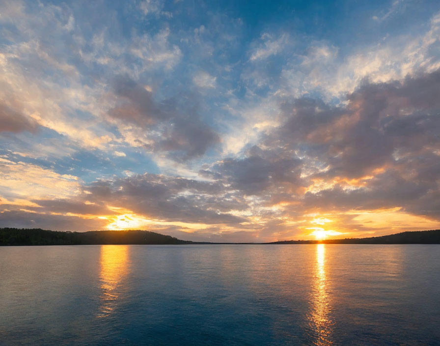 Tranquil sunset scene over a reflective lake with forest silhouettes