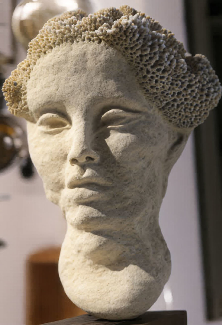 Human head sculpture with textured hair, closed eyes, and neutral expression indoors