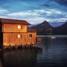 Traditional palace illuminated by warm lights near serene river and lush mountains