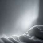 Soft white bedsheet with glowing light through window