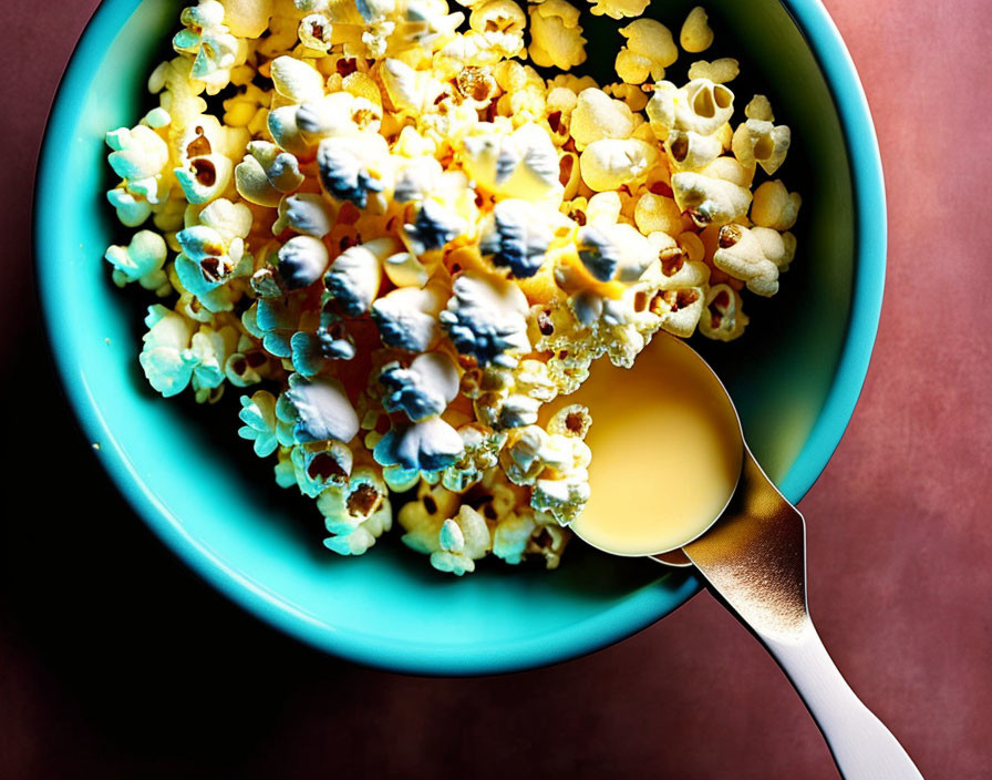 Colorful Popcorn Bowl with Melted Butter Spoon on Red Background