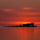 Silhouette of house at sunset with birds and drones in vibrant sky