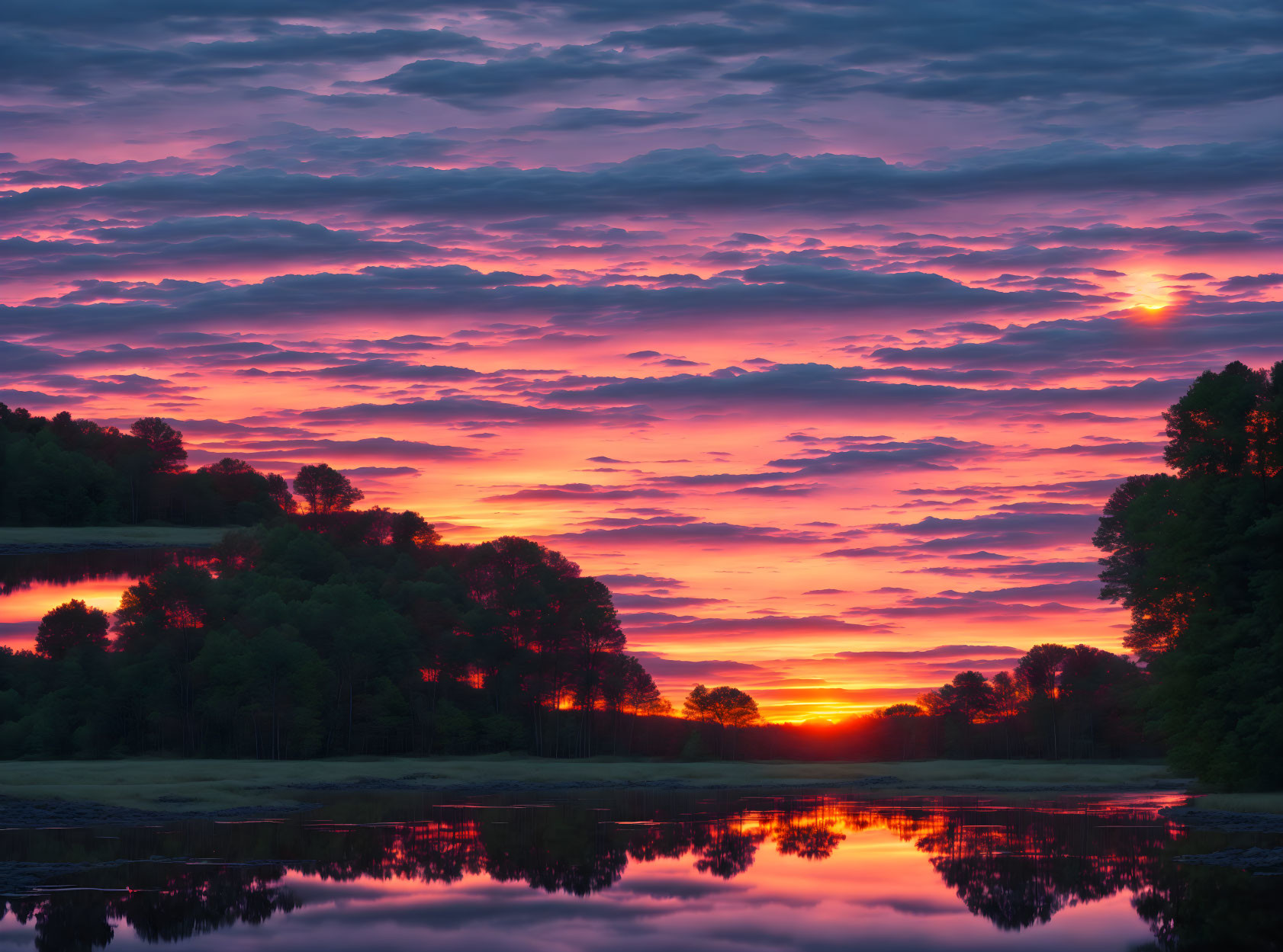 Tranquil sunrise over calm lake with pink and orange hues