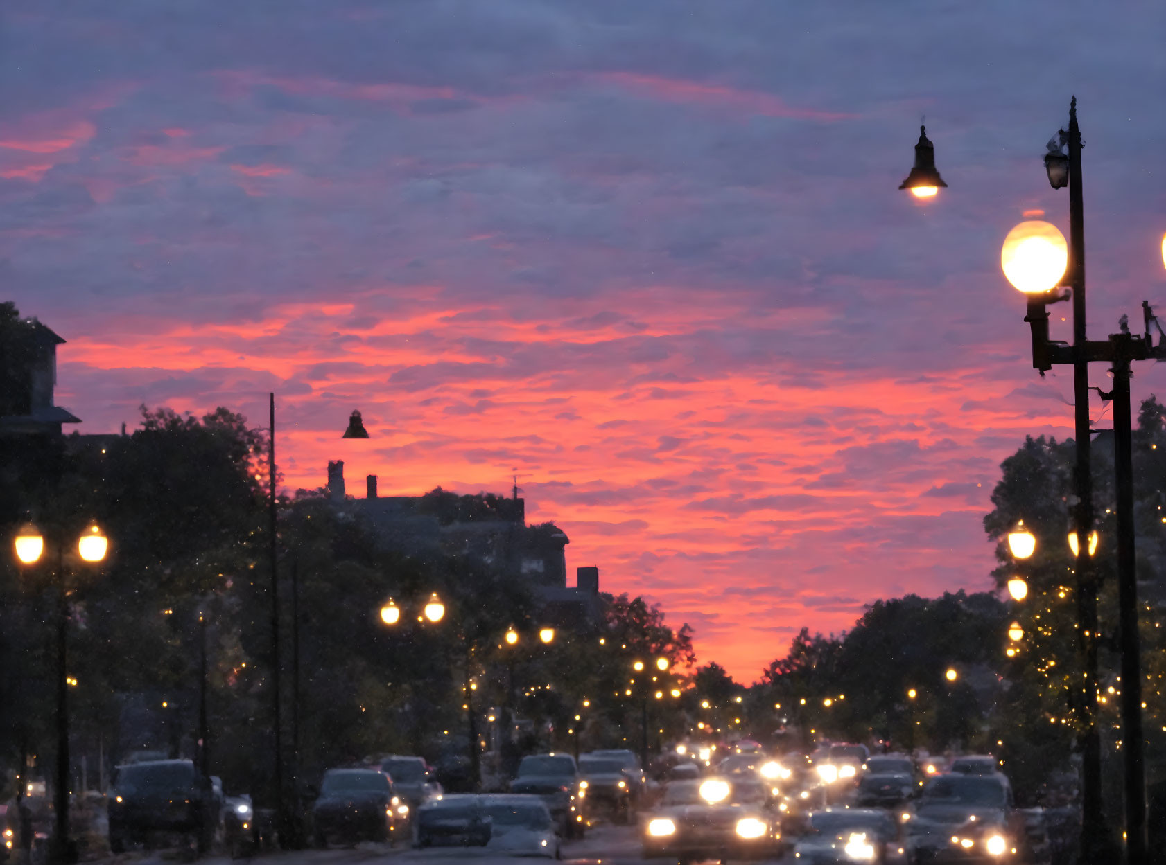 City street at sunset with pink and orange sky and traffic