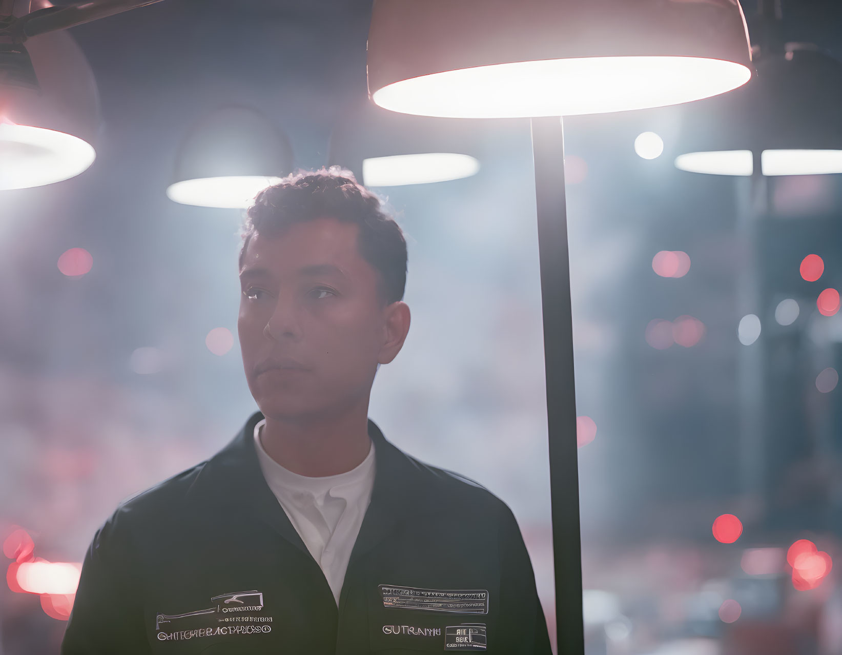 Pensive person in dark uniform under lamp in soft glowing lights