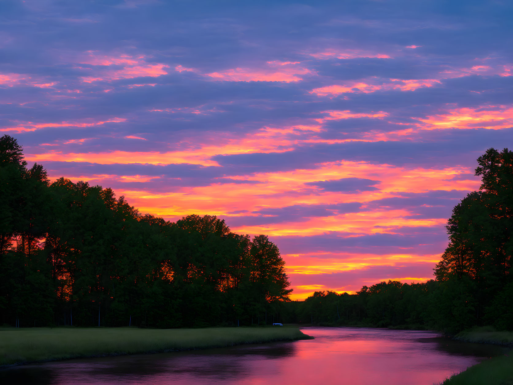 Tranquil river scene at sunset with colorful sky and reflections