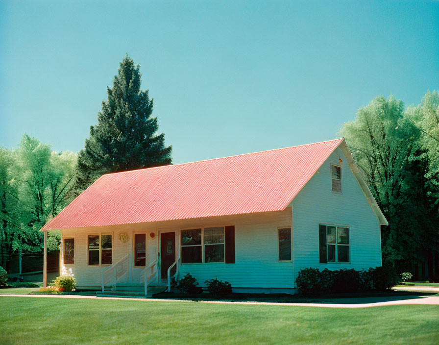 Small White House with Red Roof Surrounded by Green Trees