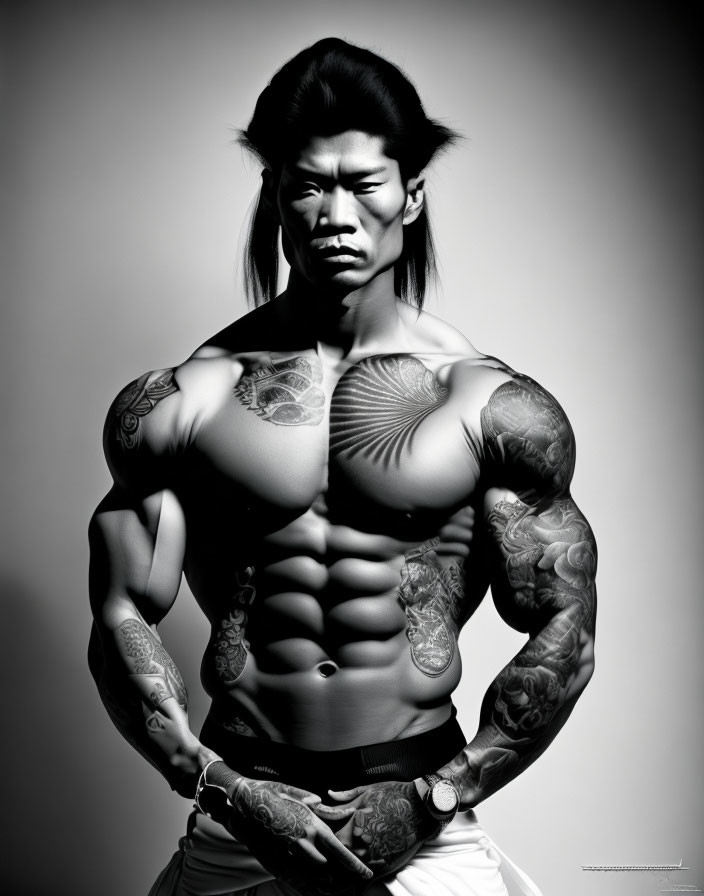 Muscular man with tattoos posing against gray background