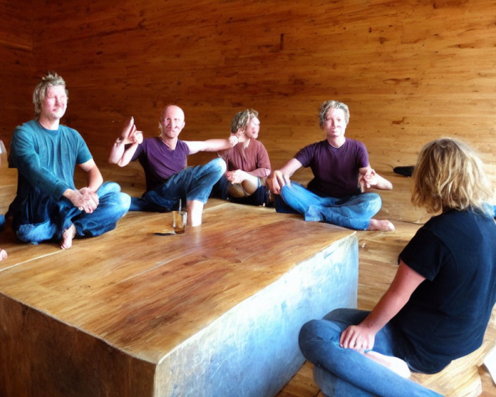 People sitting on wooden benches in a room with wood-paneled walls conversing casually