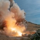 Explosion with flames and smoke near mountain landscape on wooden path