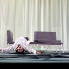 Figure in white sheet by red-lit laptop and modern chair